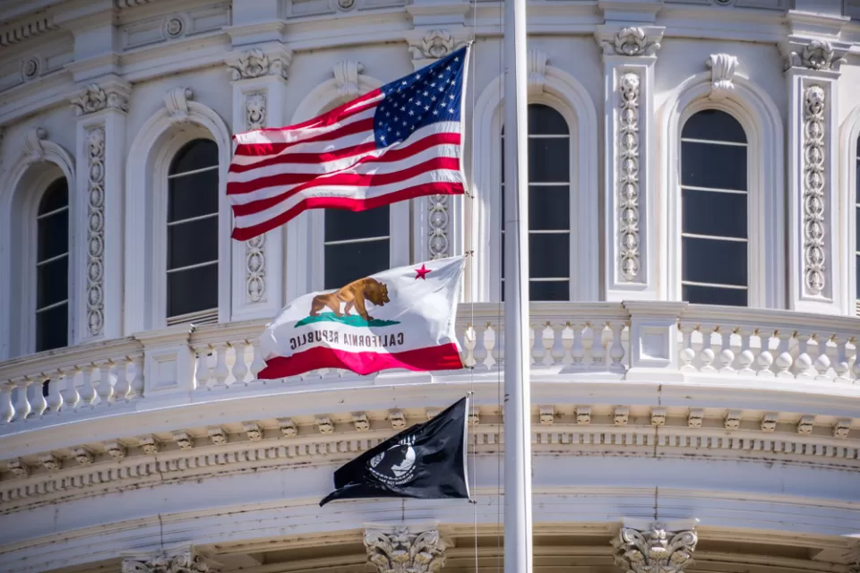 California state capitol building dome with U.S., California, and POW/MIA flags on flagpole